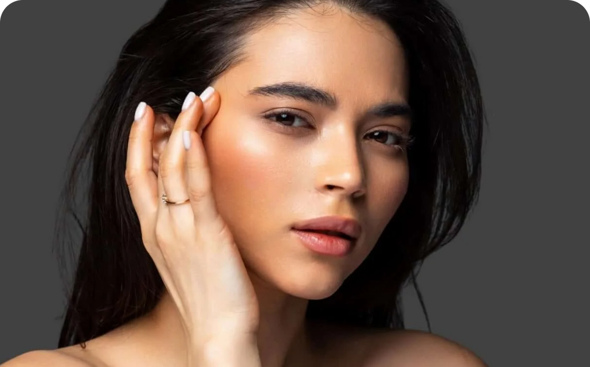 Close-up portrait of a woman with glowing skin touching her cheek for an anti aging microneedling article