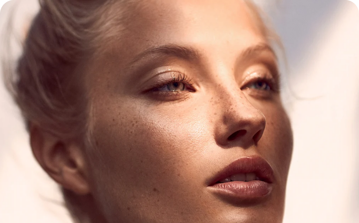 Close up of a freckled woman's face with soft makeup, illustrating clear skin for an article on acne scars and chemical peels.