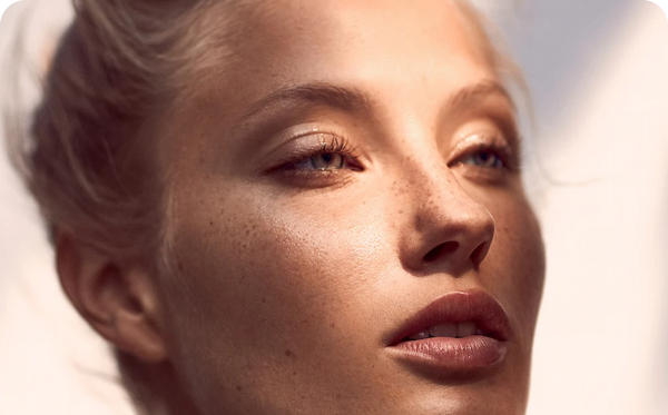 Close up of a freckled woman's face with soft makeup, illustrating clear skin for an article on acne scars and chemical peels.
